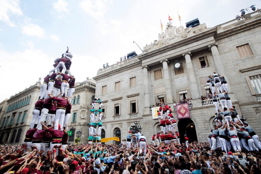 four human towers in a place with lots of people