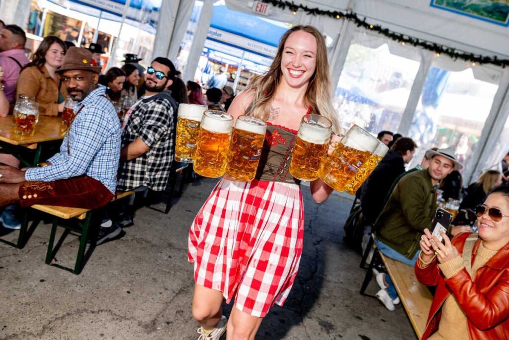 A blond girl in traditional German dress with beers in her hands.