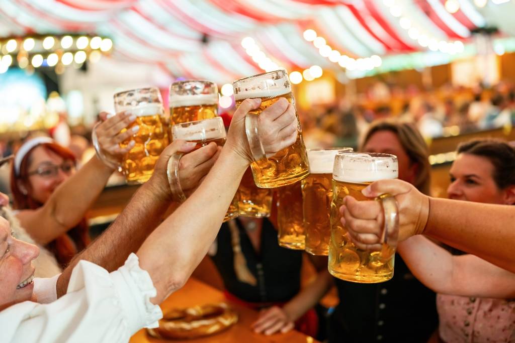 A group of people raising their beers in toast to celebrate the Oktoberfest.