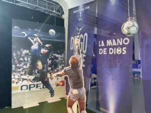 A football hanging from the ceiling and in the background a photo of the "Goal of the Century" at 'Diego Vive'.