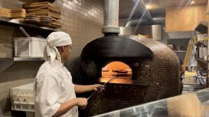 Concepto Nonna chef cooking a focaccia in the restaurant's stone oven
